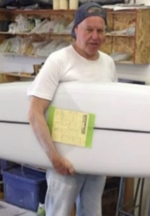 Kenneth Alan Mann holding surfboard and work order