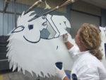Susan applying paint to the metal mustang