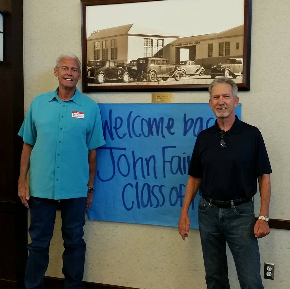 John Fairchild and Bob Lewis standing in front of Welcome Back poster