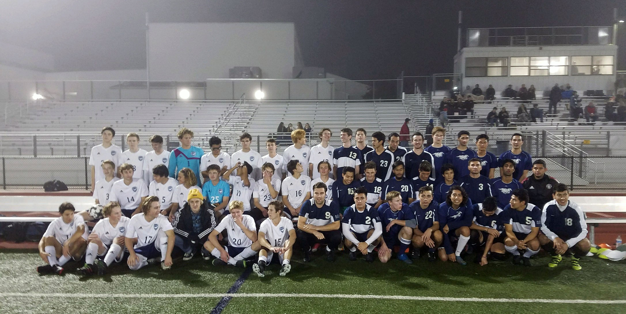 Alumni Soccer and the Current Varsity Team pose on a foggy field